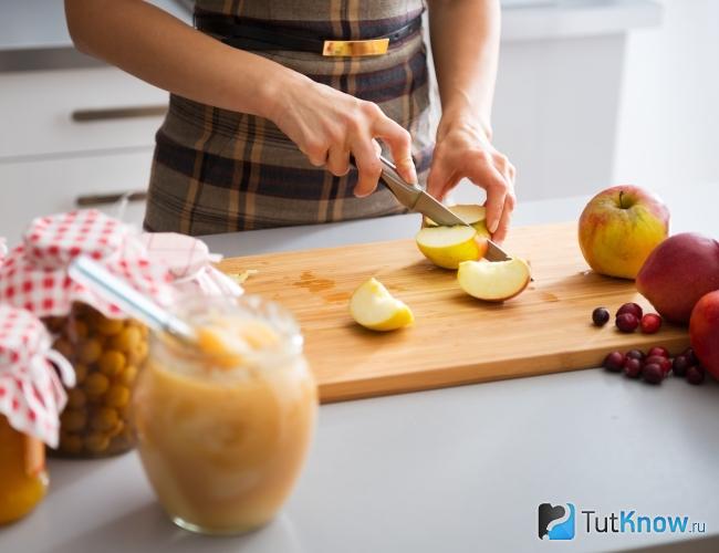 Женщина режет яблоки на повидло